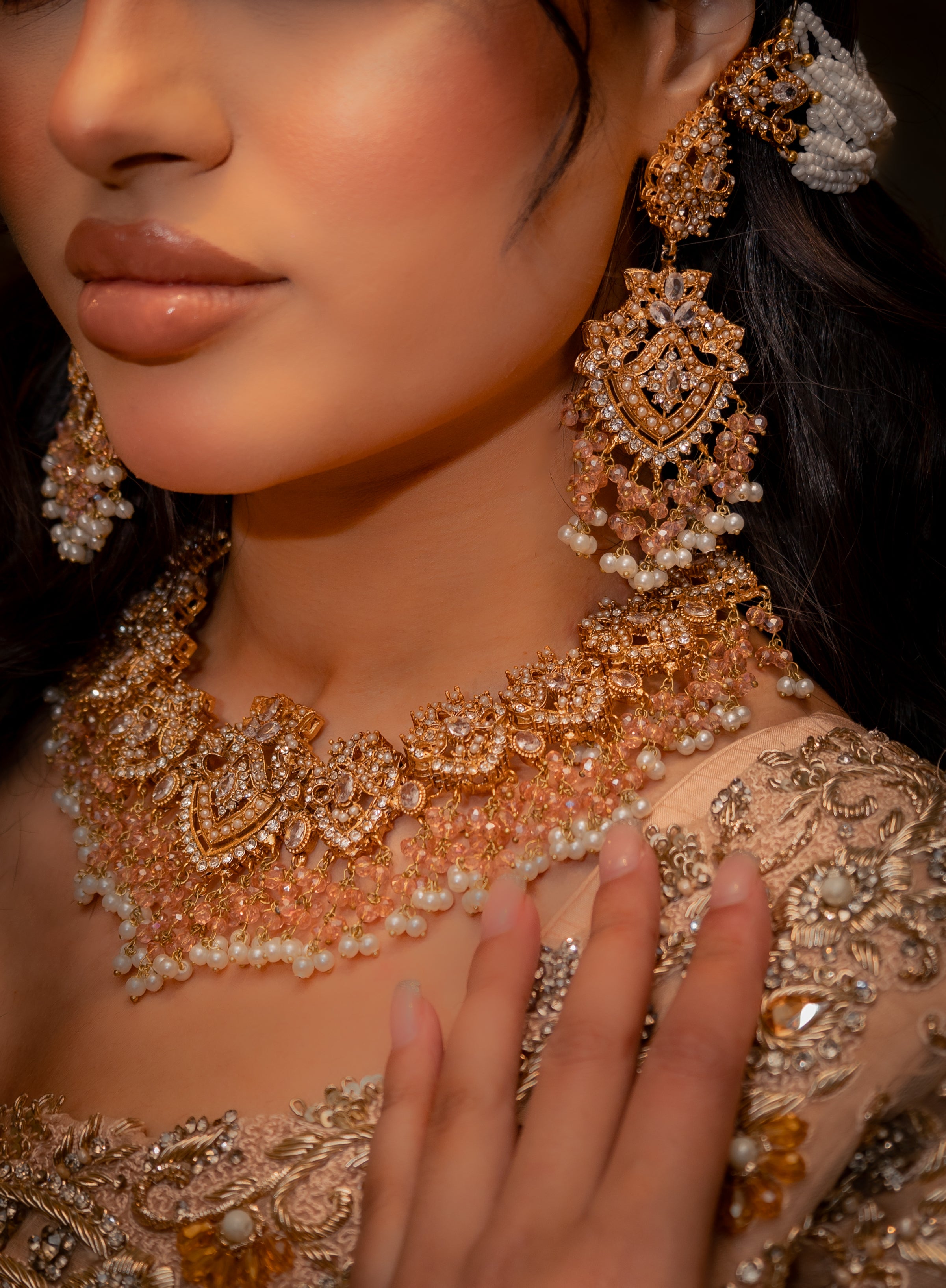 Close-up of a person wearing elaborate gold and pearl jewelry with a dark background